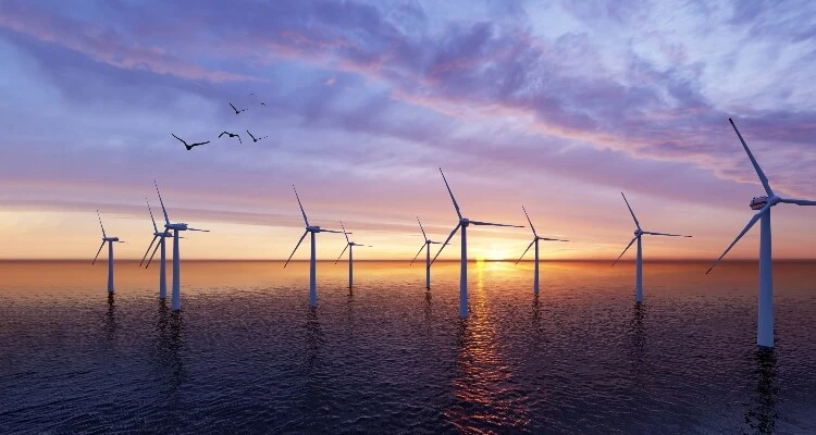 Wind turbines in sea at sunset